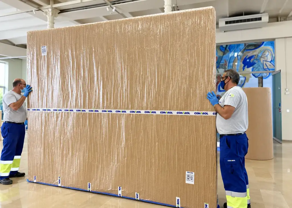 Operarios de Mudanzas Control con una obra de gran formato embalada en una sala de museo